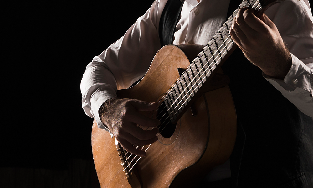 Fotografia ilustrativa de um homem tocando violão - Microfonia: o que é, por que acontece e como evitar. Harmonik Microphones